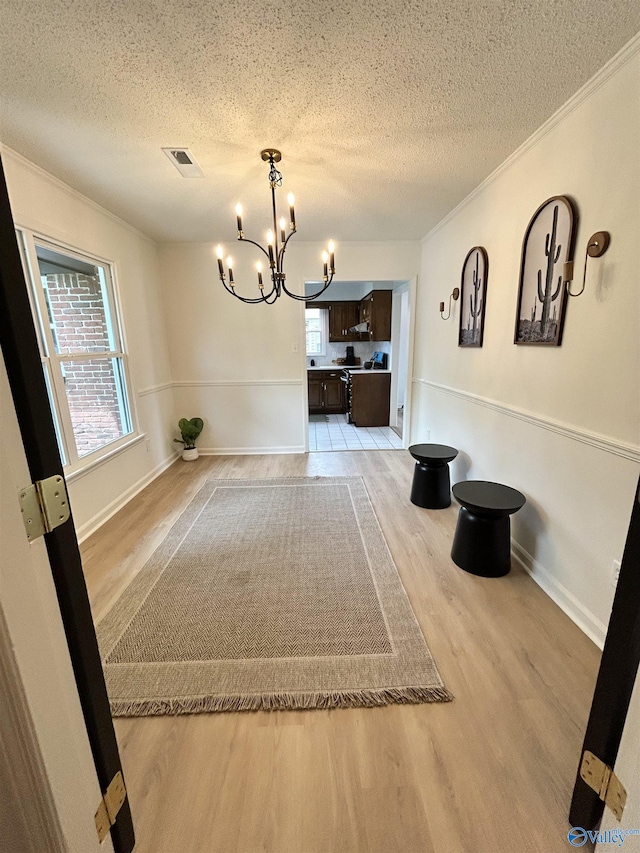 2704 Mctavish Ave SW, Decatur, AL 35603 - unfurnished dining area with a chandelier, a textured ceiling, light wood-style floors, plenty of natural light, and crown molding