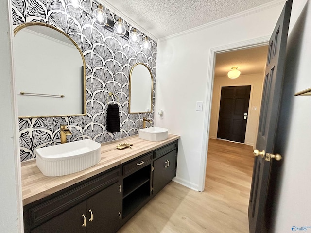 2704 Mctavish Ave SW, Decatur, AL 35603 - bathroom with wood finished floors, a textured ceiling, crown molding, double vanity, and baseboards