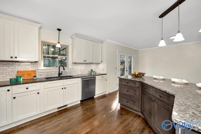 kitchen featuring dark stone countertops, sink, decorative light fixtures, and stainless steel dishwasher