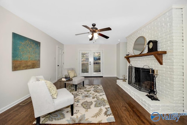 living area featuring ceiling fan, a brick fireplace, dark hardwood / wood-style flooring, and french doors