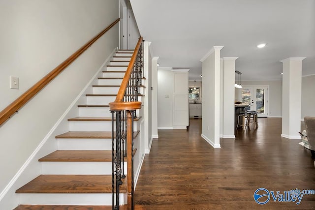 staircase with decorative columns, crown molding, and wood-type flooring