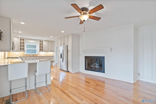 kitchen featuring sink, light stone counters, stainless steel fridge with ice dispenser, kitchen peninsula, and white cabinets