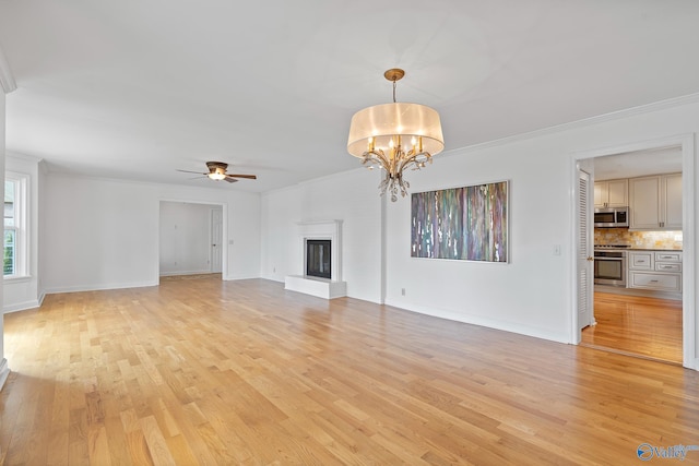 unfurnished living room with ornamental molding, ceiling fan with notable chandelier, and light hardwood / wood-style flooring