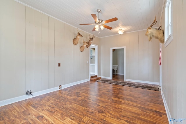 spare room featuring dark wood-type flooring, wood ceiling, ornamental molding, and ceiling fan