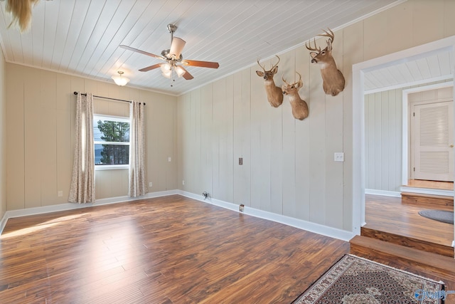 spare room featuring crown molding, dark wood-type flooring, wooden ceiling, and ceiling fan