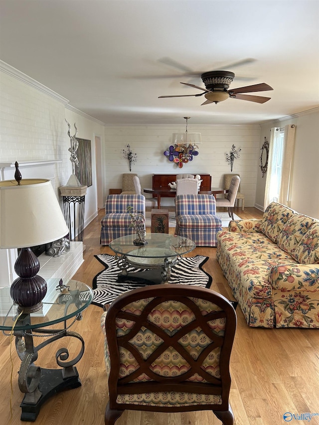 living room with crown molding, ceiling fan, and light wood-type flooring