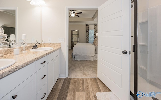 bathroom with ceiling fan, vanity, a tray ceiling, and hardwood / wood-style floors