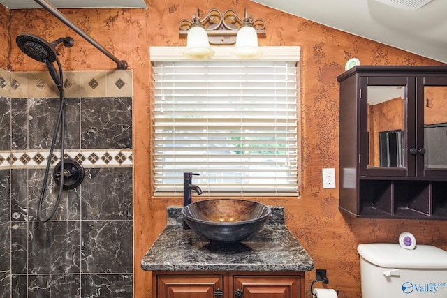 bathroom with vanity, toilet, and a tile shower