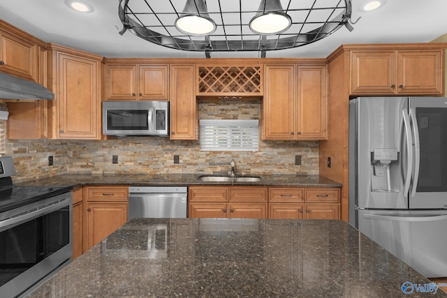 kitchen featuring dark stone countertops, stainless steel appliances, sink, and backsplash