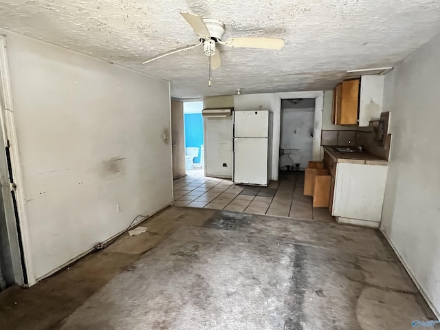 kitchen with light tile patterned flooring, white fridge, and a textured ceiling