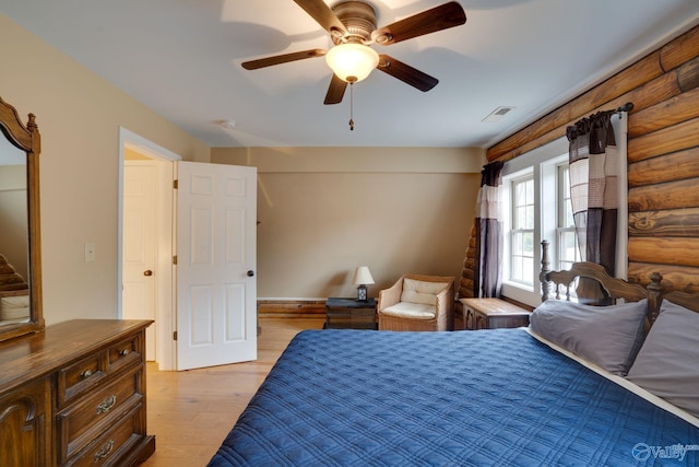 bedroom with log walls, light hardwood / wood-style floors, and ceiling fan