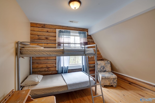 bedroom featuring rustic walls and hardwood / wood-style floors