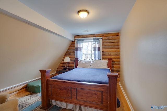 bedroom featuring hardwood / wood-style floors and log walls