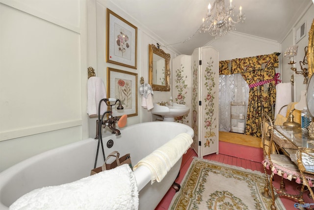 bathroom with a notable chandelier, a washtub, vaulted ceiling, and ornamental molding