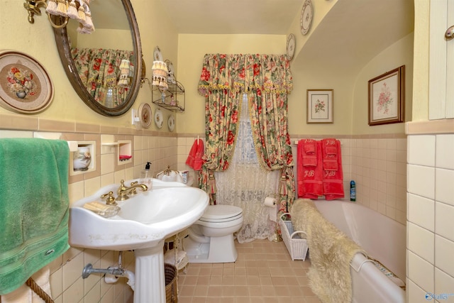 bathroom featuring tile patterned flooring, a washtub, and tile walls