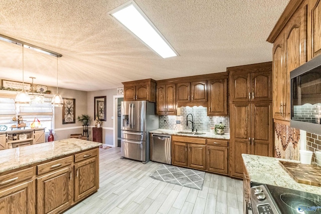 kitchen with decorative backsplash, sink, light wood-type flooring, and appliances with stainless steel finishes