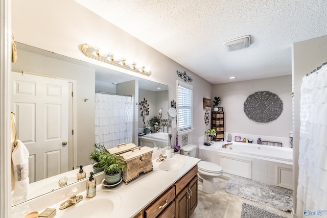 bathroom featuring tiled bath, vanity, a textured ceiling, and toilet