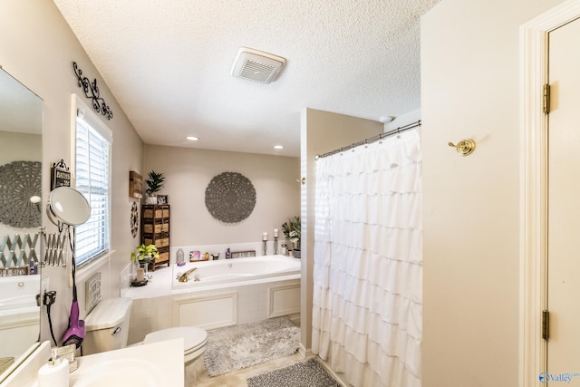 bathroom featuring tile patterned flooring, toilet, a textured ceiling, and tiled tub