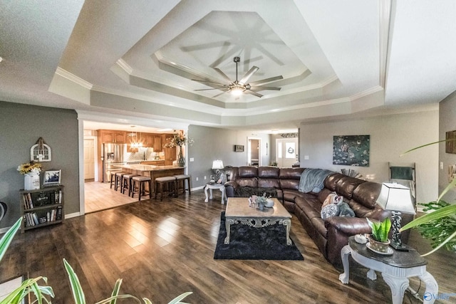 living room featuring hardwood / wood-style flooring, a raised ceiling, ceiling fan, and ornamental molding