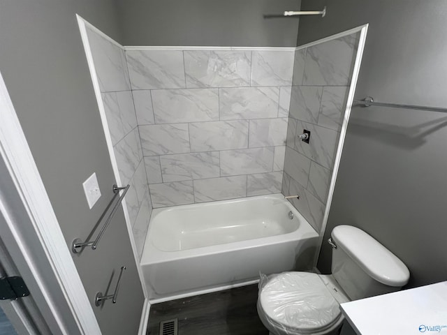 full bathroom with hardwood / wood-style floors, vanity, tiled shower / bath combo, and toilet