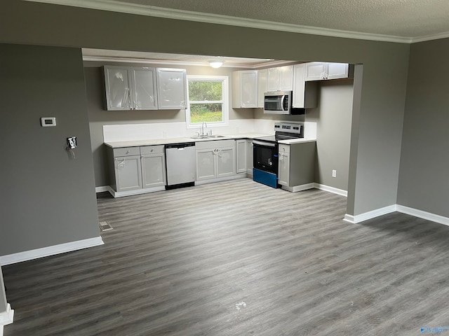 kitchen with sink, light wood-type flooring, a textured ceiling, appliances with stainless steel finishes, and ornamental molding