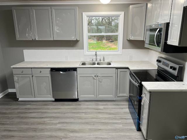 kitchen with gray cabinetry, sink, light hardwood / wood-style floors, and appliances with stainless steel finishes