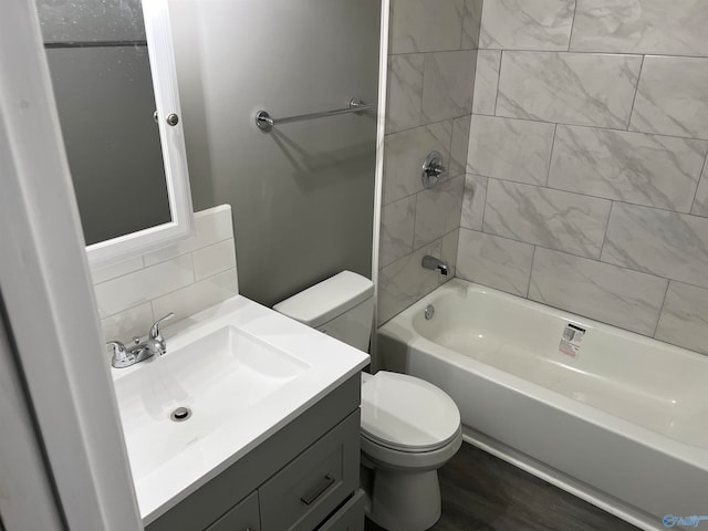 full bathroom with vanity, wood-type flooring, tiled shower / bath combo, and toilet