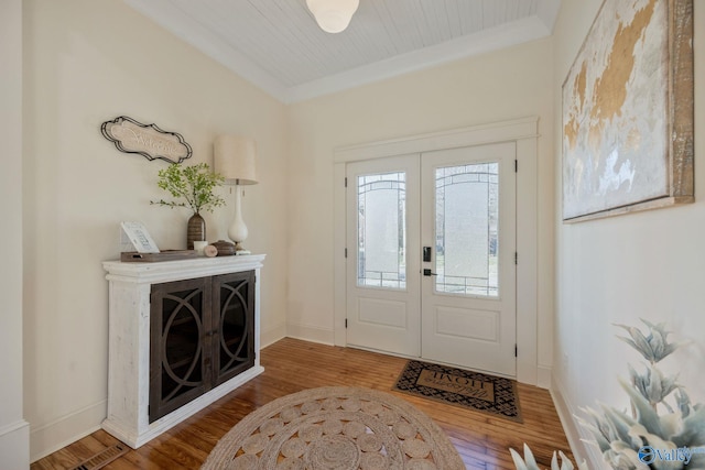 entrance foyer with baseboards, ornamental molding, wood finished floors, and french doors