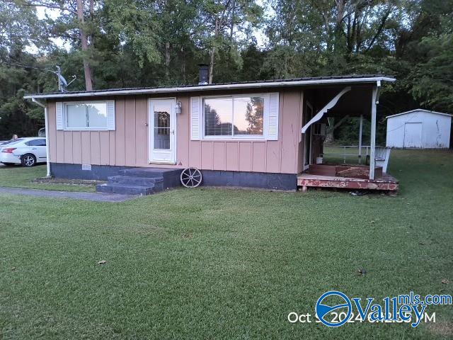 view of front facade with a storage shed and a front lawn