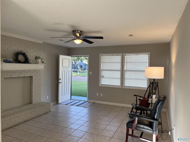 sitting room with light tile patterned floors, a textured ceiling, visible vents, baseboards, and a brick fireplace