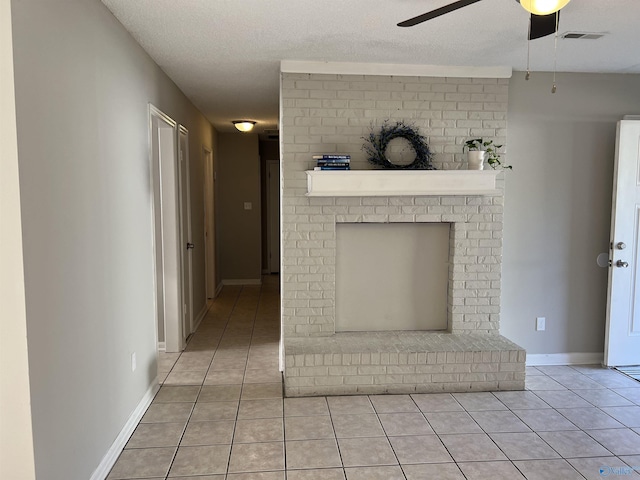 corridor featuring light tile patterned floors, baseboards, visible vents, and a textured ceiling