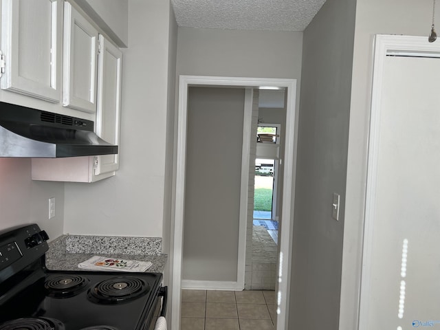 kitchen featuring light tile patterned floors, black range with electric stovetop, white cabinetry, a textured ceiling, and under cabinet range hood