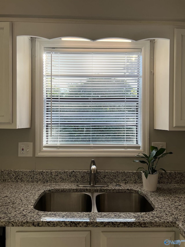 interior details with light stone countertops, white cabinets, and a sink