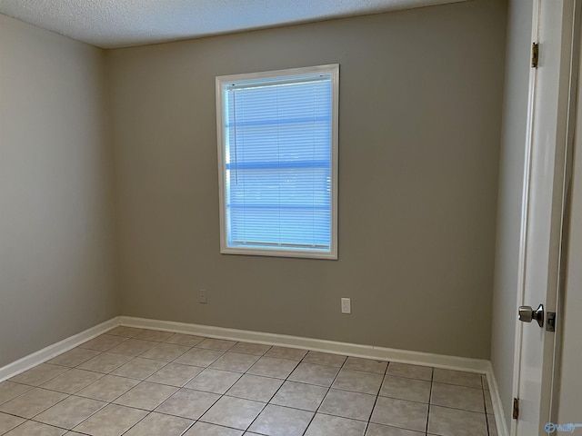 unfurnished room featuring a textured ceiling, baseboards, and light tile patterned floors