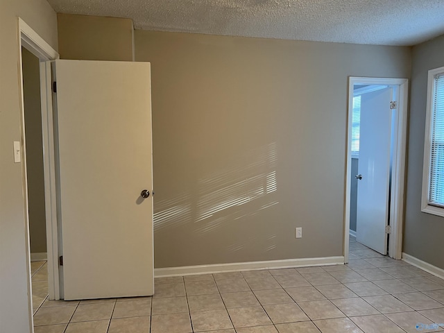 unfurnished room featuring light tile patterned floors, baseboards, and a textured ceiling