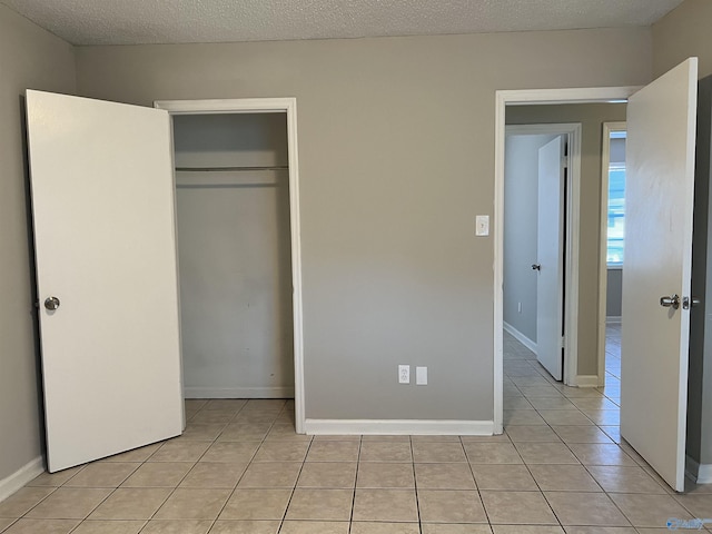 unfurnished bedroom with light tile patterned floors, a textured ceiling, and a closet