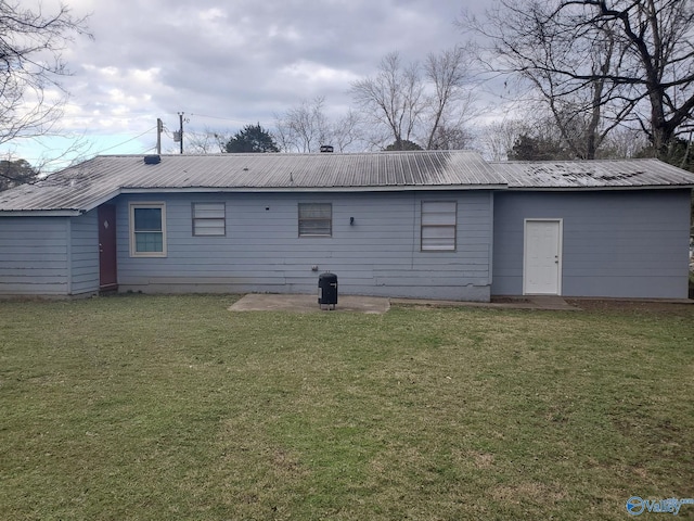 back of house featuring metal roof and a lawn