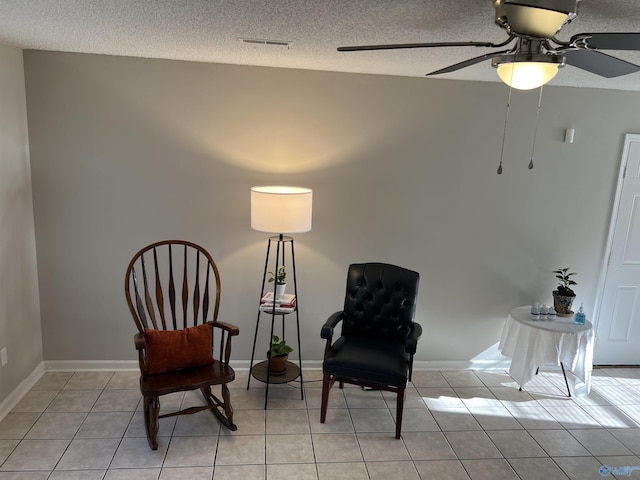 living area with light tile patterned floors, a textured ceiling, visible vents, and baseboards