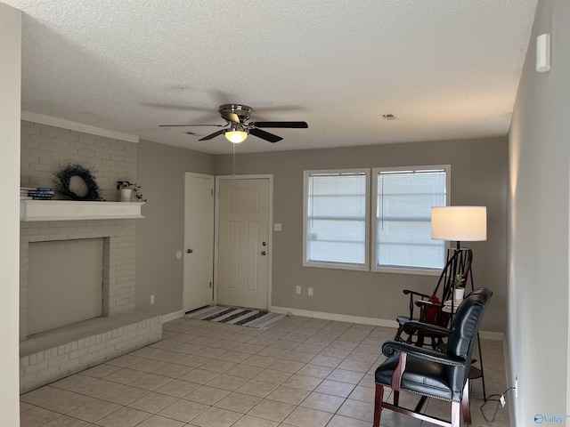 foyer featuring light tile patterned floors, a ceiling fan, a brick fireplace, a textured ceiling, and baseboards