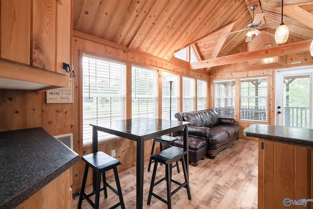 interior space featuring light hardwood / wood-style flooring, wood ceiling, vaulted ceiling with skylight, wood walls, and ceiling fan