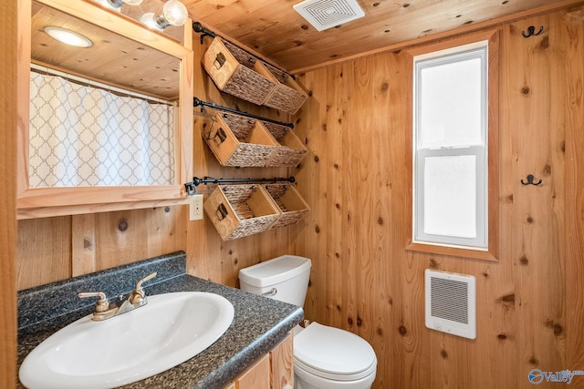 bathroom featuring a healthy amount of sunlight, wood walls, and toilet