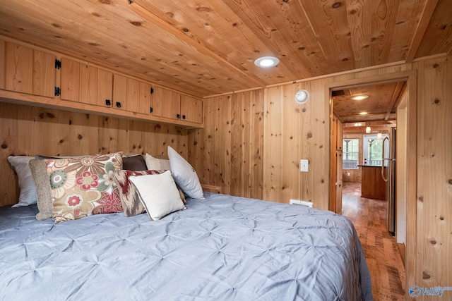 bedroom with wood walls, stainless steel refrigerator, light hardwood / wood-style flooring, and wood ceiling