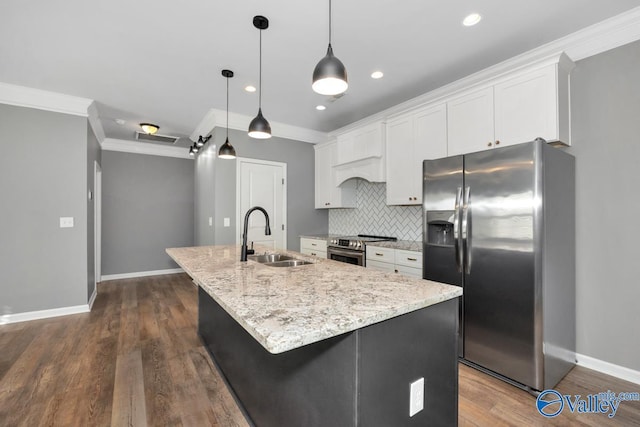 kitchen with white cabinets, appliances with stainless steel finishes, a center island with sink, and sink