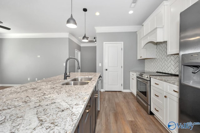 kitchen with light stone counters, stainless steel appliances, sink, decorative light fixtures, and white cabinets