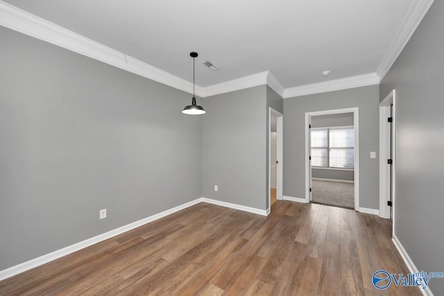 empty room featuring hardwood / wood-style floors and crown molding