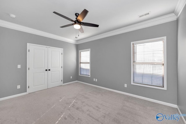 unfurnished bedroom with light carpet, a closet, ceiling fan, and crown molding