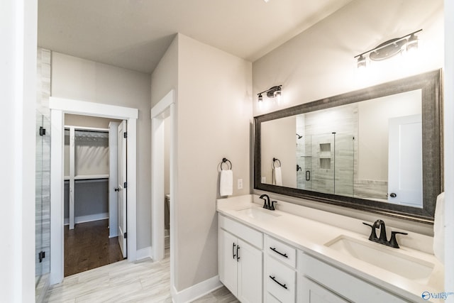 bathroom featuring a shower with door and vanity