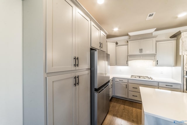 kitchen with stainless steel appliances, gray cabinetry, dark hardwood / wood-style floors, tasteful backsplash, and crown molding