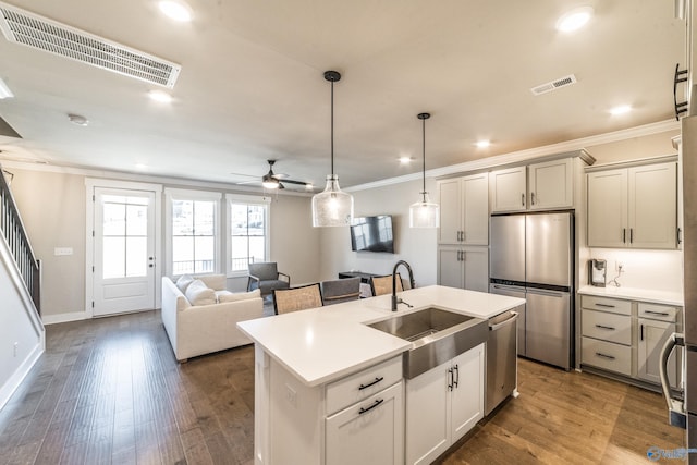 kitchen with hardwood / wood-style floors, pendant lighting, a center island with sink, sink, and appliances with stainless steel finishes