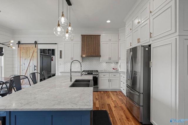 254 Whitlow Rd, Decatur, AL 35603 - kitchen featuring appliances with stainless steel finishes, a barn door, custom range hood, white cabinets, and pendant lighting